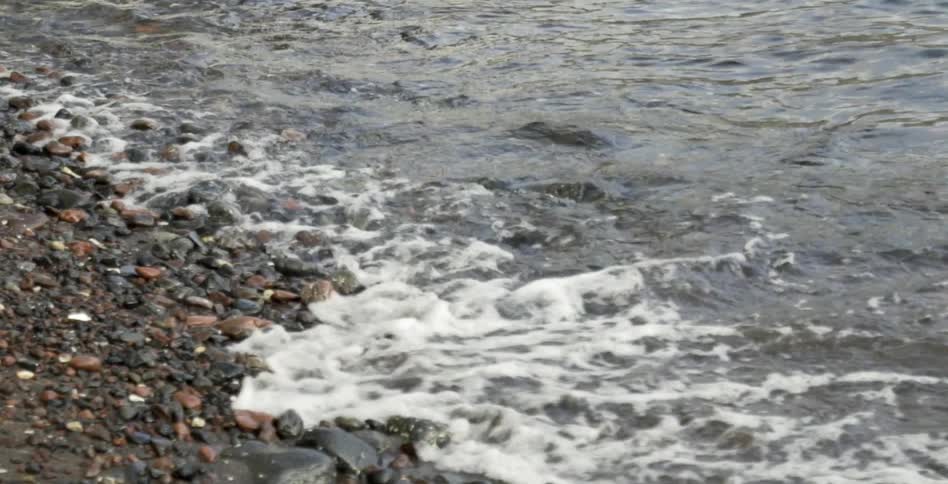 Waves flow and crash along a rock lined shore