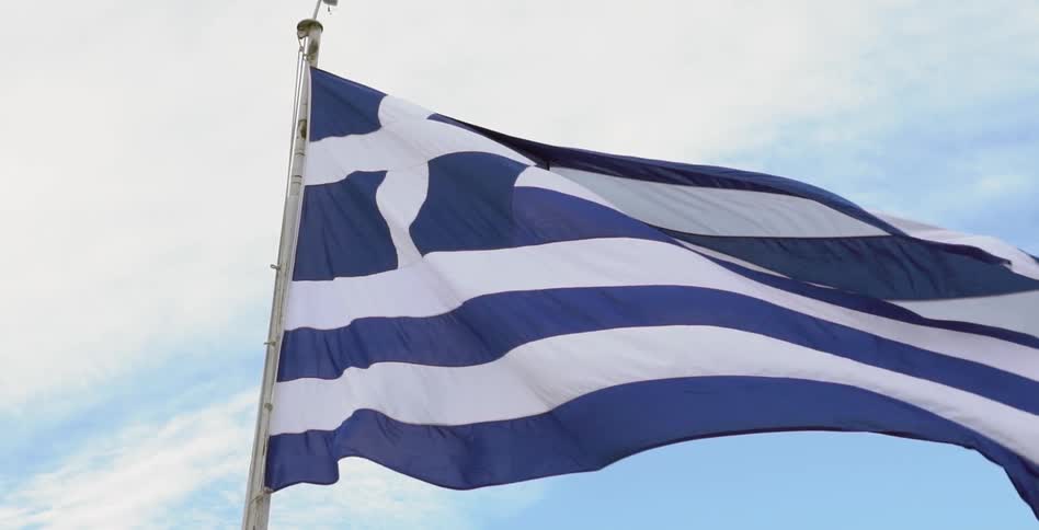 The flag of greece breezes in the wind against a cloudy sky