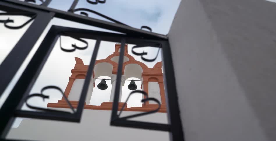 A wrought iron fence against a bell monument
