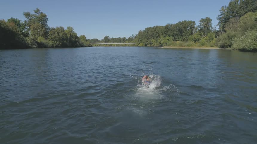 Person swims in water away from camera above and behind them