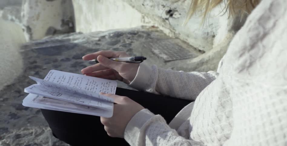 A woman writes in a notebook outside