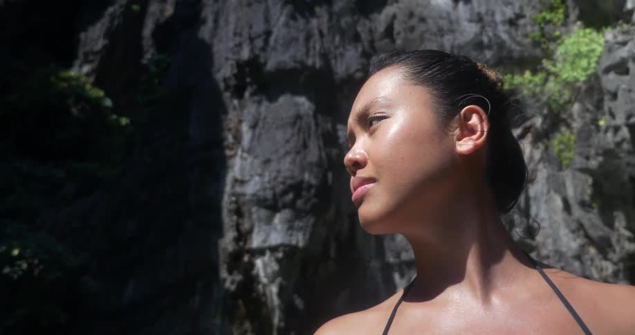 A woman stars around as she stands by a cliff