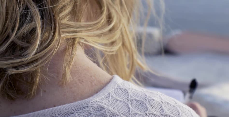 Blond woman writing with a pen