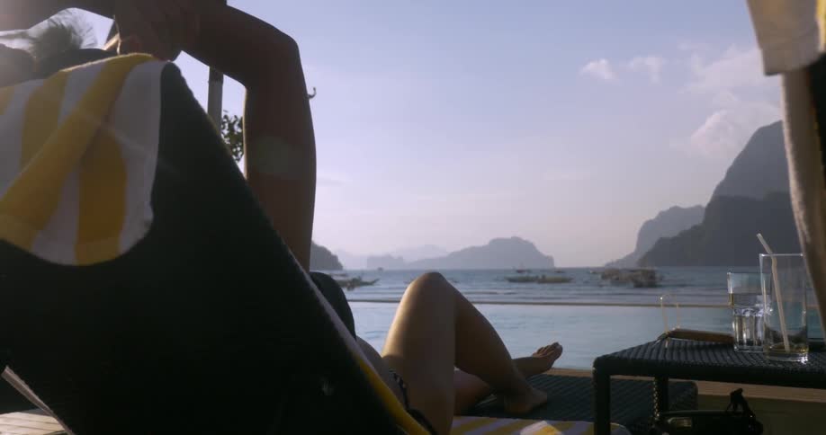 A woman sunbathes in a beach chair on the shoreline