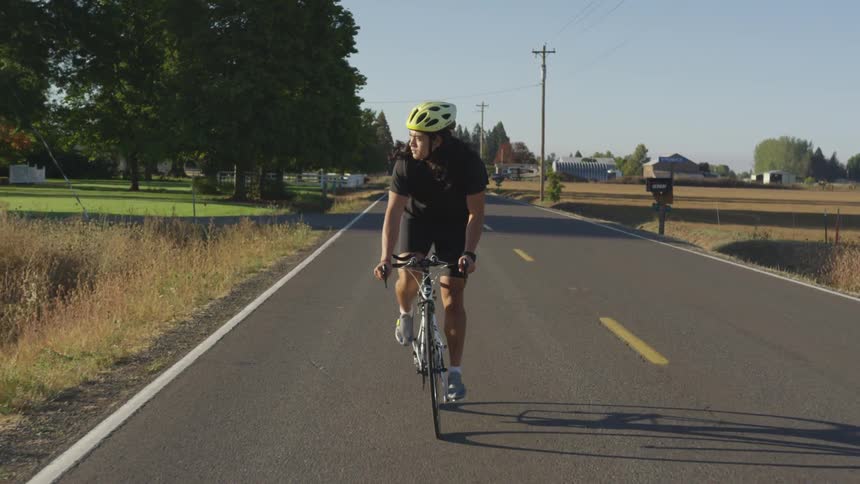 A woman is riding on her bicycle on a road and looking to her right side