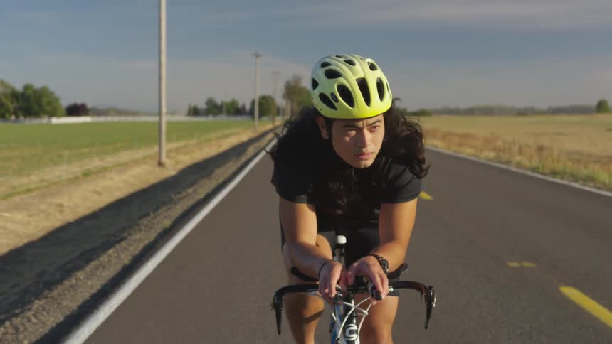 A bicyclist cycling down a country road