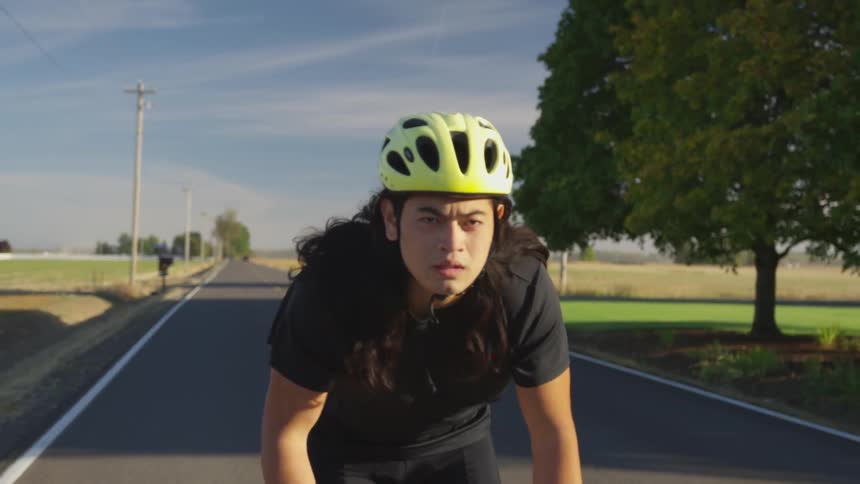 A man pedals a bicycle on a rural road