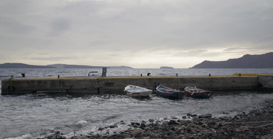 Three small boats are docked on a cloudy day