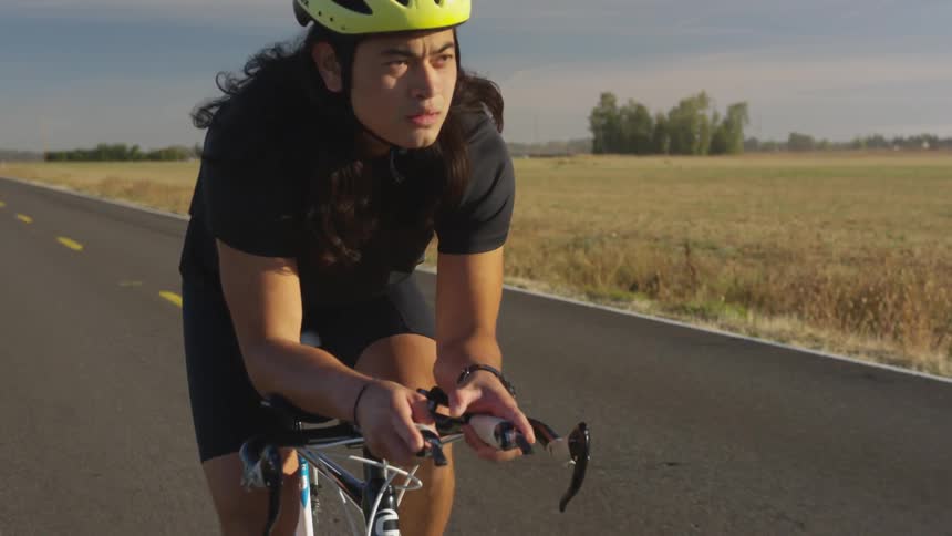 A bicyclist cycling down a rural road