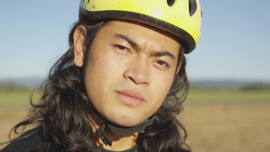 A man wears a bicycle helmet while in a field