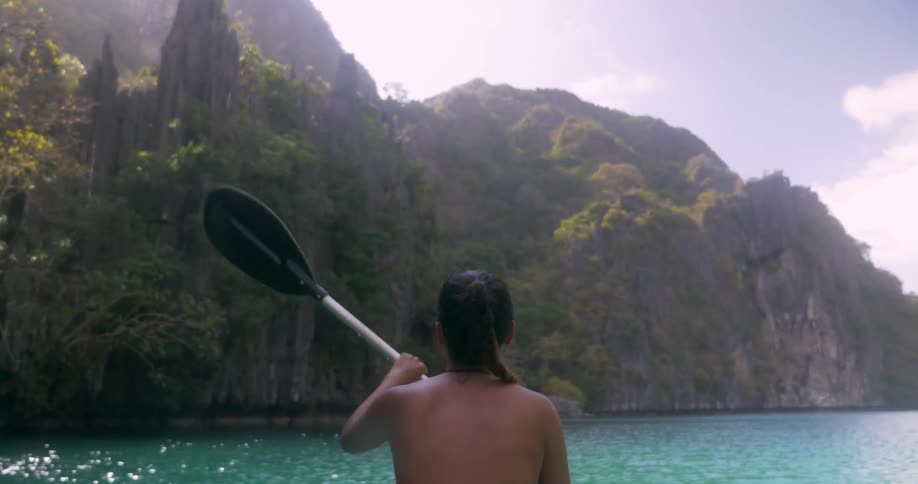 Ponytailed brunette slowly paddling on beautiful blue waters