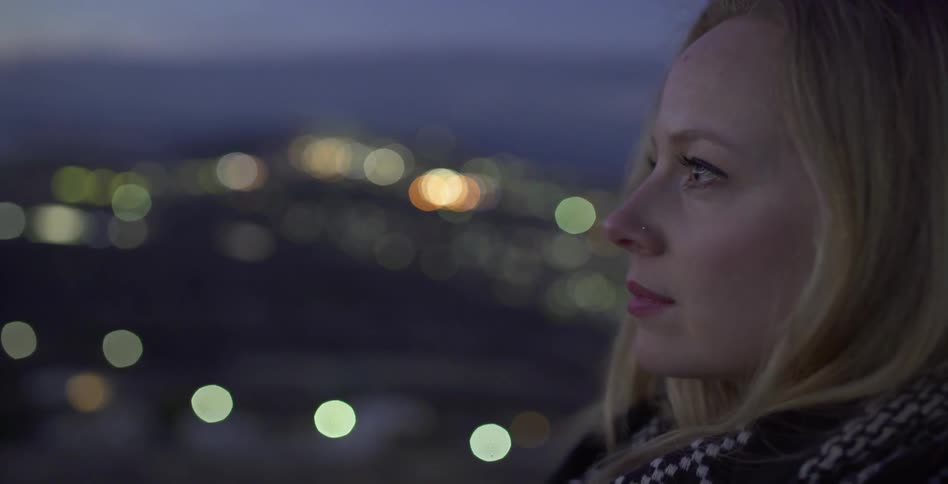 Woman standing lost in thought outside at night