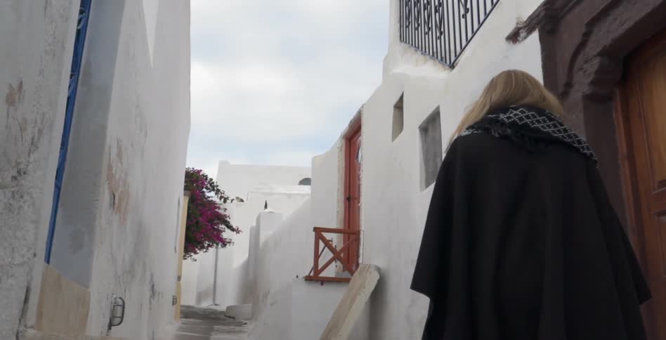 A woman walks past a home up some steps on a cloudy day