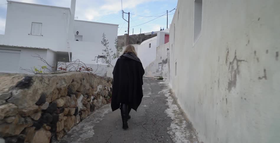 A woman walks along a distressed alleyway