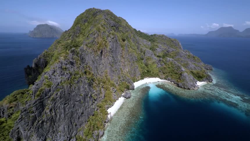 A large rock cliff is surrounded by water on all sides