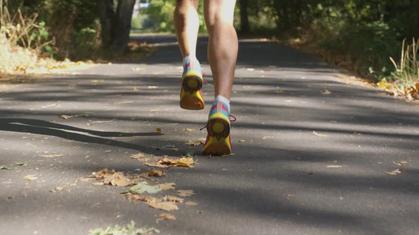 Person runs along road in shorts during the day