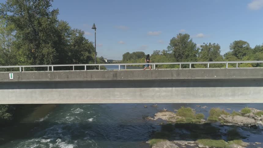 A man with long hair running on a bridge