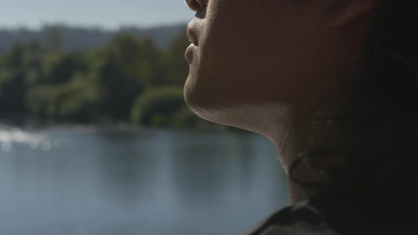Person facing a body of water surrounded by trees