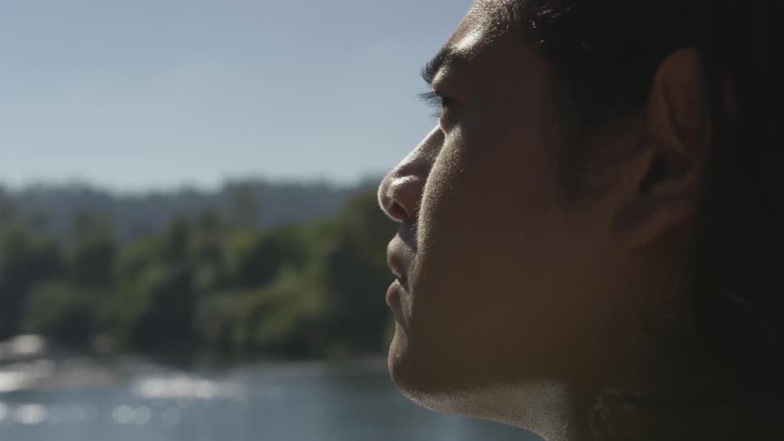 A pensive woman gazes out over a body of water