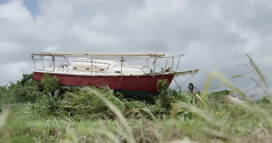 A boat sits on a bed of grass on a cloudy day