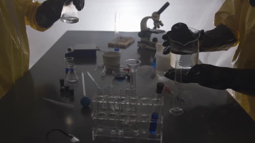 Two people pour liquids into scientific equipment