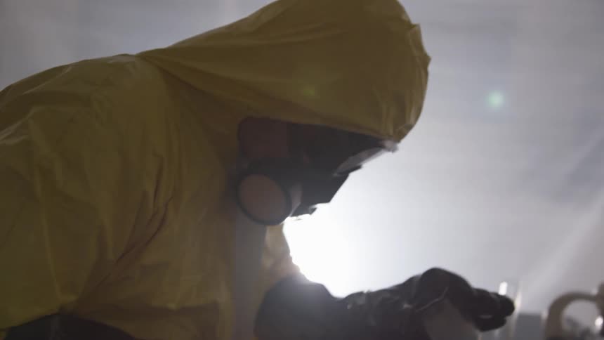 A chemist in a hazmat suit shaking a chemical