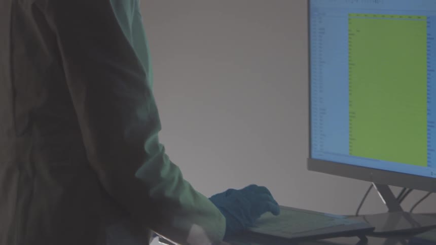A woman with gloves and goggles on types on a keyboard