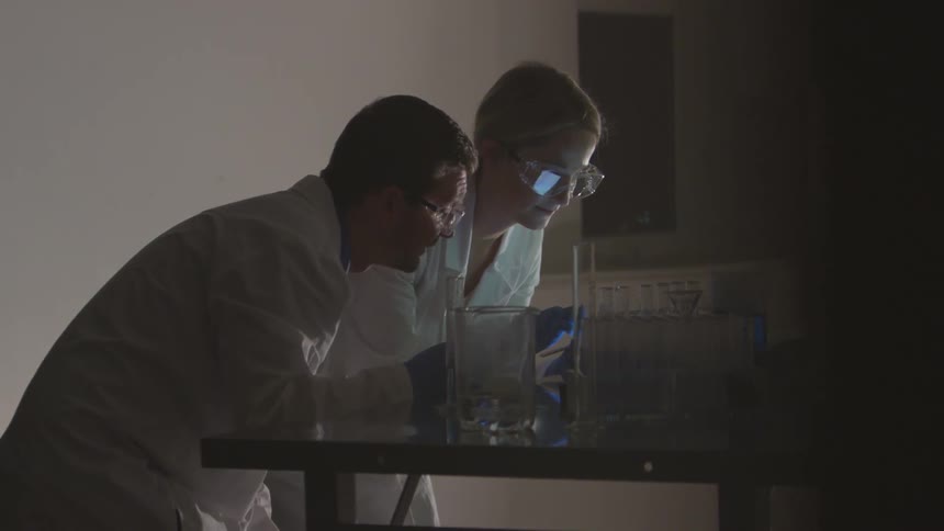 Scientists perform an experiment with blue liquid in a test tube