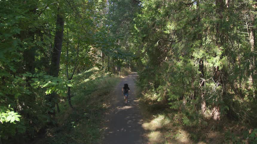 Person runs down trail in forest