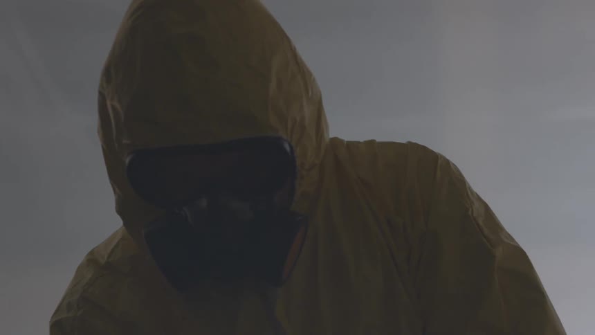 Man zips up protective suit while wearing a breathing apparatus
