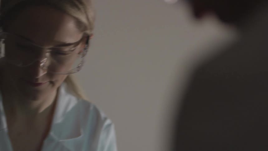 Scientist with protective glasses and a lab coat looks down and works
