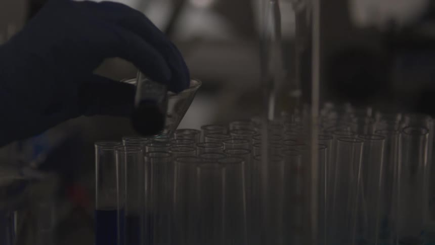 A person pouring liquid from a test tube