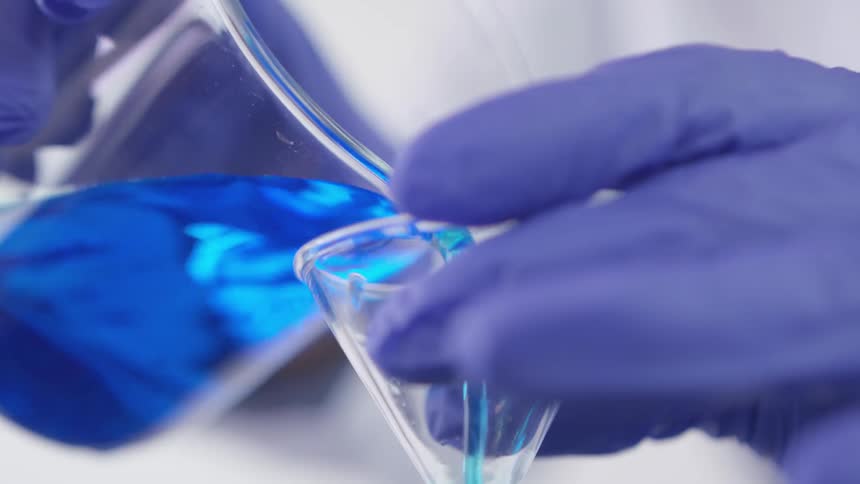 A scientist pouring items out of a beaker