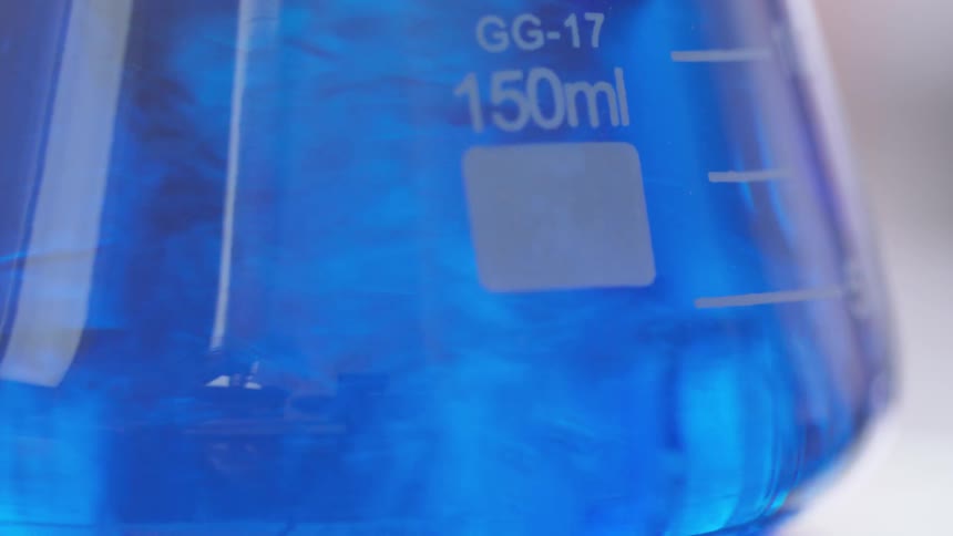 Blue fluid inside a beaker is spinning round