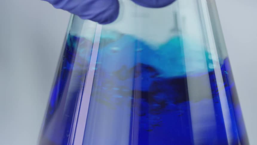 A person mixing liquid in a flask in a lab