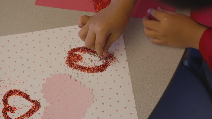 A girl sprinkling glitter on a piece of paper