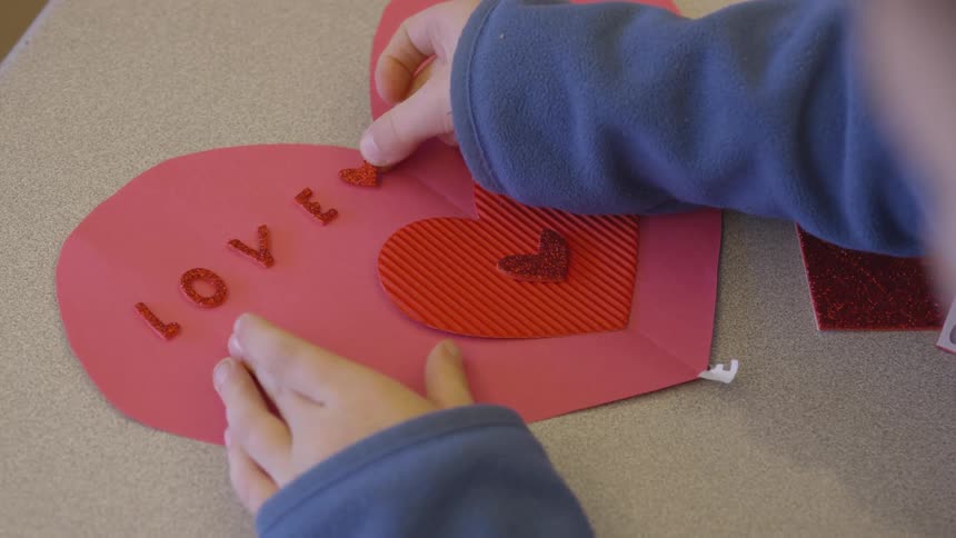 A child is making a valentines day card