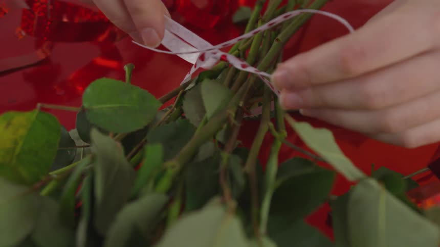 A woman tying a ribbon around roses
