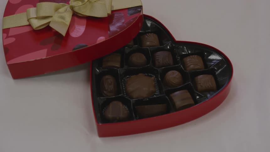 Heart shaped box of chocolates with a gold bow on cover