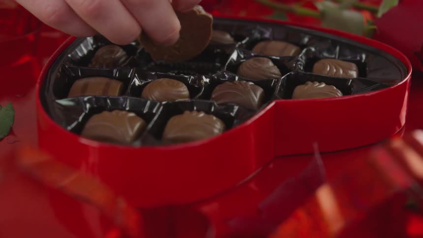 A person picking up a chocolate from a gift box