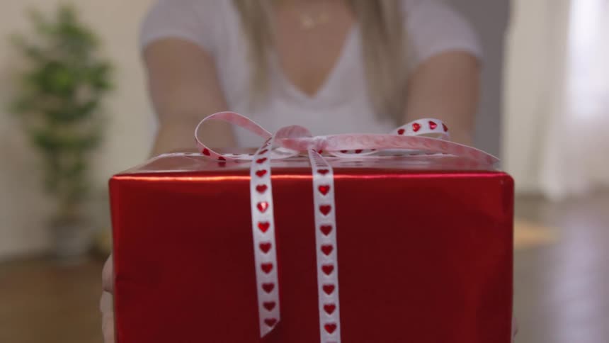 A woman presents a wrapped gift