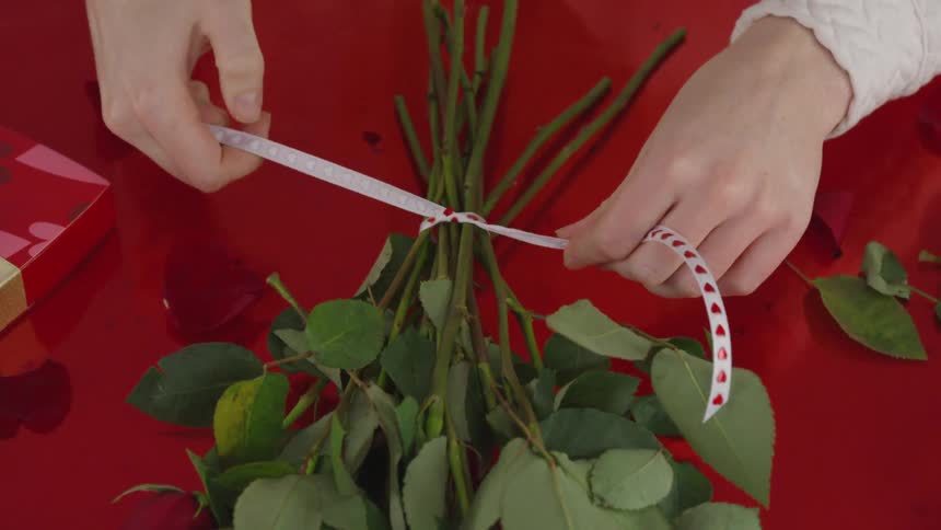 Ribbon with hearts being tied around rose stems