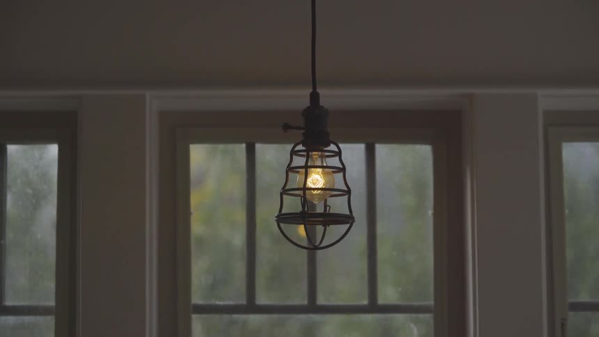 Single light fixture hangs in front of a window