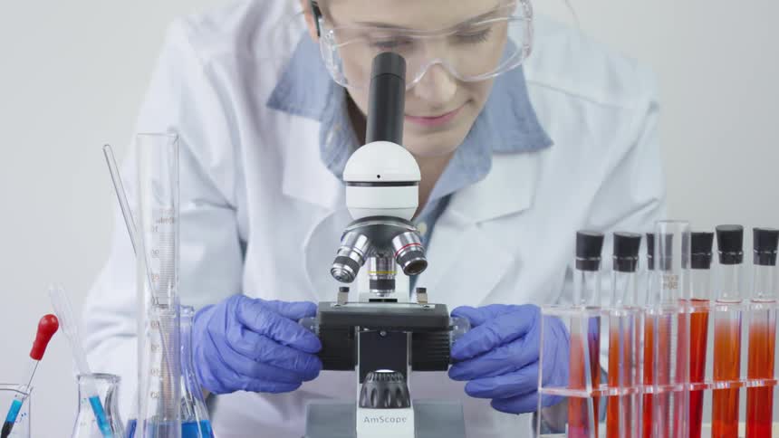 A woman using a microscope to look at items on a slide