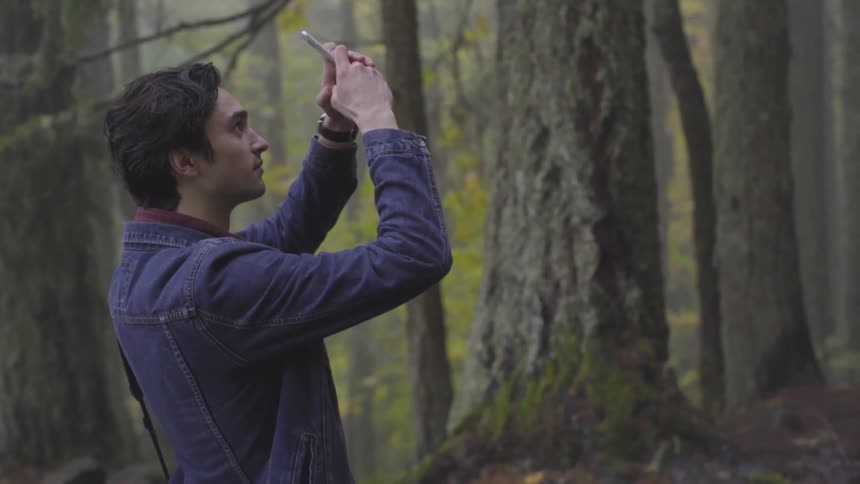 Man taking a photo in the woods