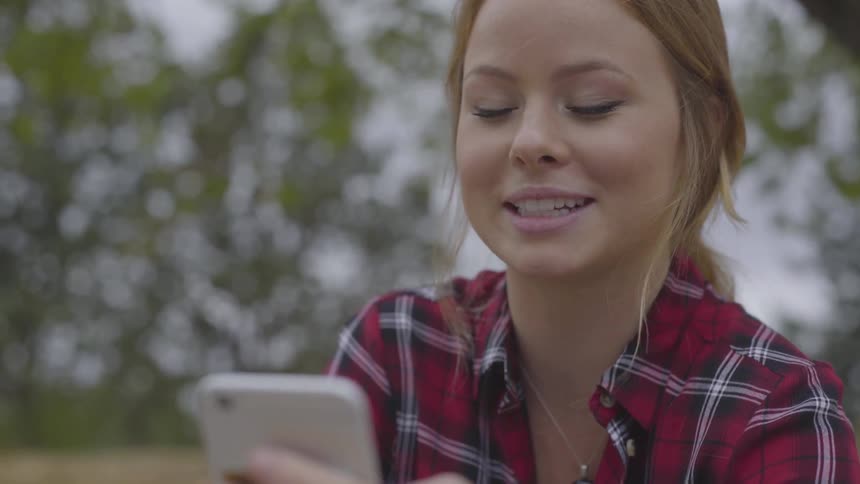 A woman laughing while using a cell phone