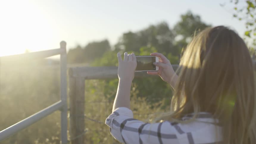 Woman uses a smartphone to take a picture of the sunset