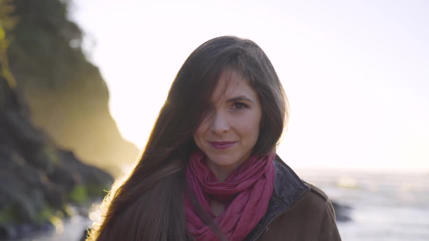 A woman wearing a scarf standing at the edge of the sea