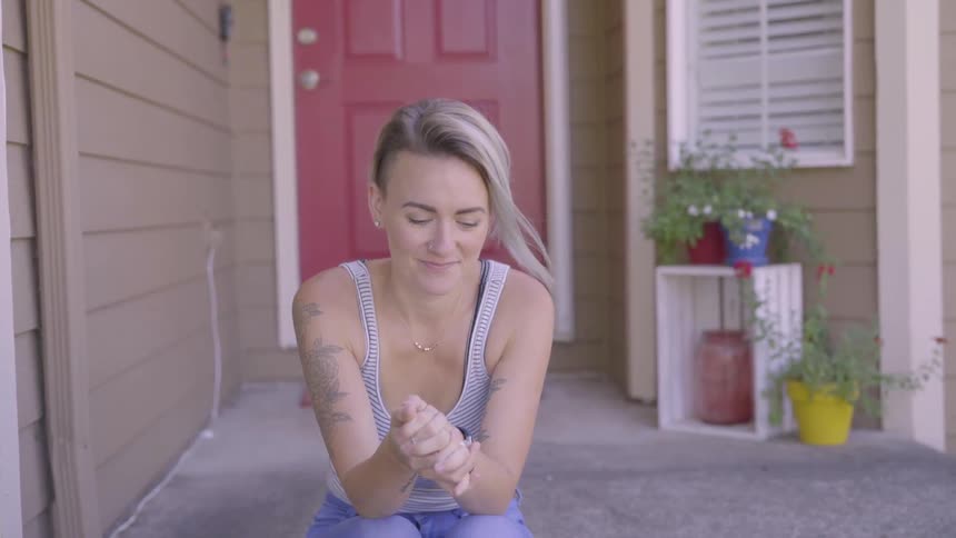 A woman is sitting outside of a house
