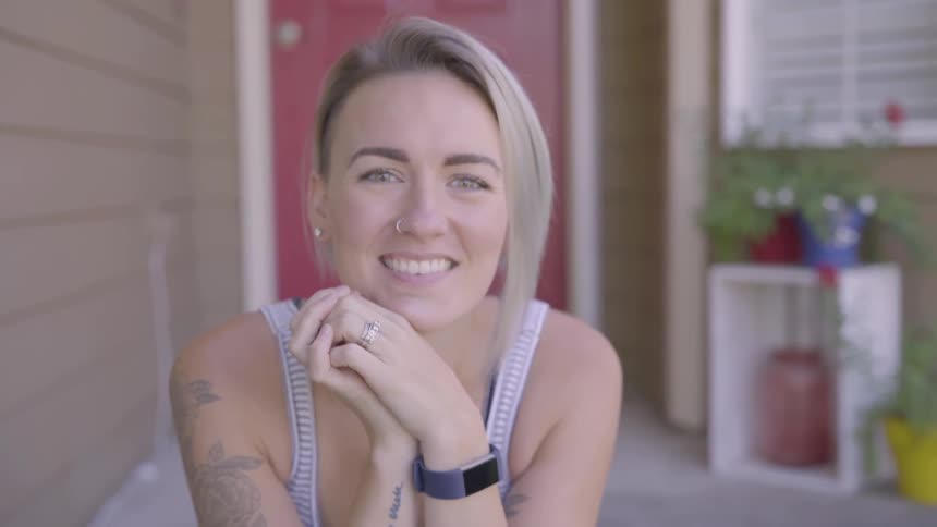 Woman looks into a camera while sitting on her front step